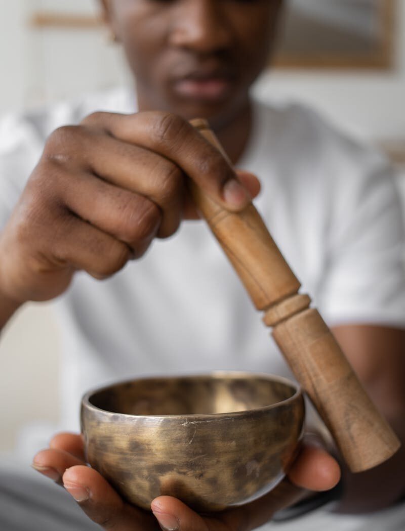 Close-up of a person using a singing bowl for meditation. Focus on hands and bowl.