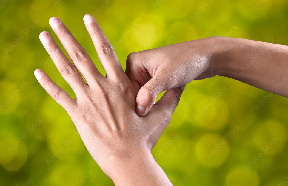 female hands make acupressure on the arm over beautiful green background